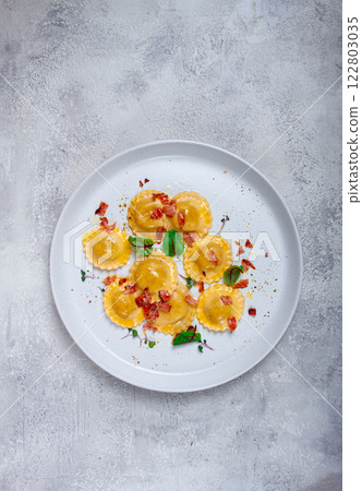 fresh ravioli, with butter, spices and herbs, fried bacon, on the table, top view, light background, no people, 122803035