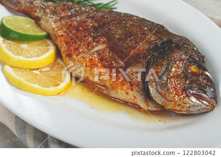 baked dorado fish, in the oven, fried dorado, with spices and herbs, on a white plate, top view, homemade, no people, 122803042