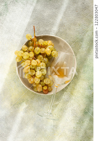 a branch of white grapes, on a gray plate, with a glass of white wine, top view, natural light, food concept, no people, 122803047