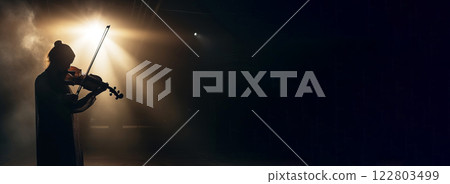 Violinist at a concert playing traditional classical music on a vintage violin. Performer under spotlights in the haze. 122803499