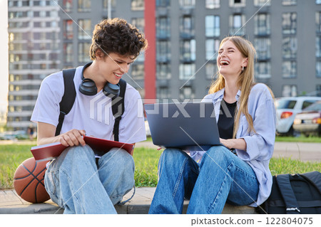 Teenage college students guy and girl laughing having fun together, sitting outdoor Teenage college students guy and girl laughing having fun together, sitting outdoor 122804075