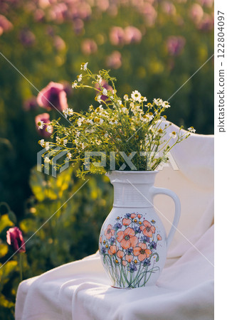 Still life with flowers and a chair in a field of poppies at sunset Still life with flowers and a chair in a field of poppies at sunset 122804097