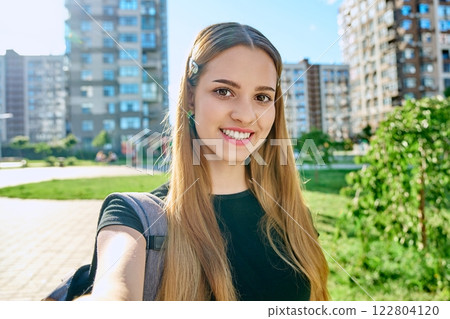 Selfie portrait smiling student teenager girl looking at webcam outdoor summer city 122804120