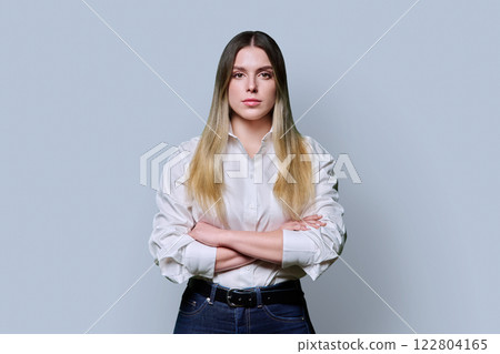 Portrait of young confident serious woman in white shirt on gray background 122804165