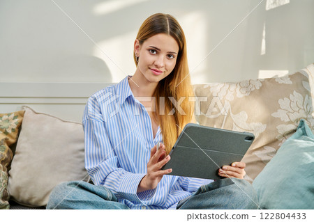 Portrait of female student on couch with digital tablet, studying at home Portrait of female student on couch with digital tablet, studying at home 122804433