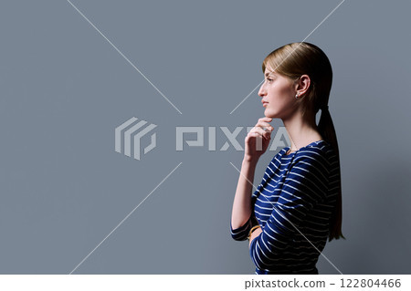 Profile view, young serious female looking forward on gray studio background 122804466