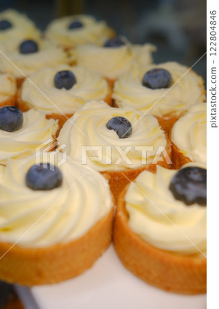 beautiful white cheesecake tart with fresh blueberries in shortcrust pastry basket placed on a white plate on the counter perfect dessert for a bakery or cafe sweet indulgence for food photography 122804846