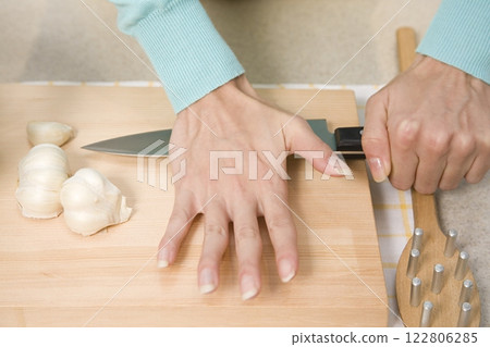 Person crushing garlic on a kitchen cutting board close view background Person crushing garlic on a kitchen cutting board close view background 122806285