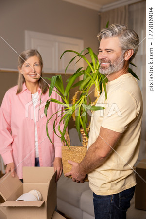 Happy senior couple unpacking cardboard boxes together in their new apartment 122806904