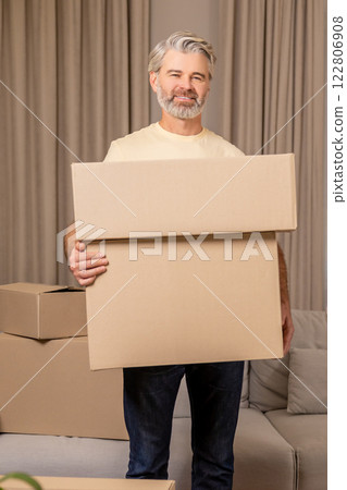 Happy senior bearded man packing cardboard boxes during relocation Happy senior bearded man packing cardboard boxes during relocation 122806908