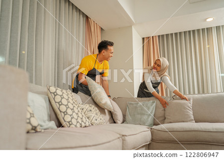 A Joyful Couple Enthusiastically Arranging Their New Sofa in a Modern Living Room A Joyful Couple Enthusiastically Arranging Their New Sofa in a Modern Living Room 122806947