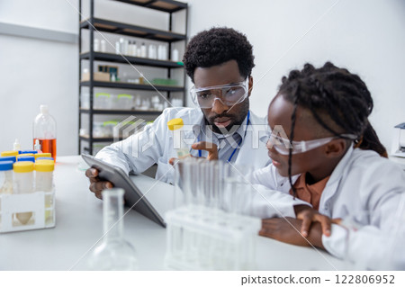Male teacher of science showing to a school girl how to use vacutainers Male teacher of science showing to a school girl how to use vacutainers 122806952