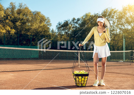 Active sporty adult woman enjoying summertime lifestyle playing tennis on court 122807016
