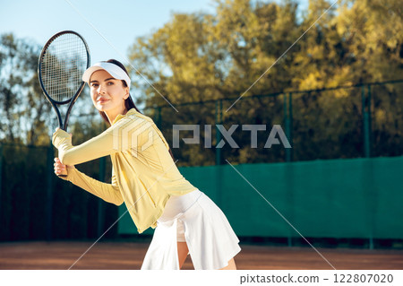 Competitive woman tennis player during game training at open air tennis court on sunny day Competitive woman tennis player during game training at open air tennis court on sunny day 122807020