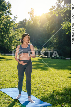 Pregnant woman on a third trimester holding her belly and looking thoughtful 122807034