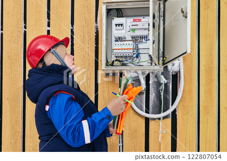 Field service engineer works on an energy meter in cold weather gear. 122807054