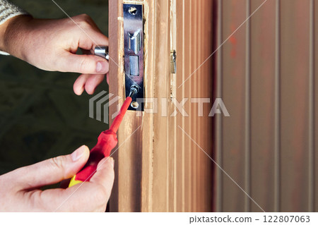 Joiner carefully fitting sash lock into wooden door edge. Joiner carefully fitting sash lock into wooden door edge. 122807063
