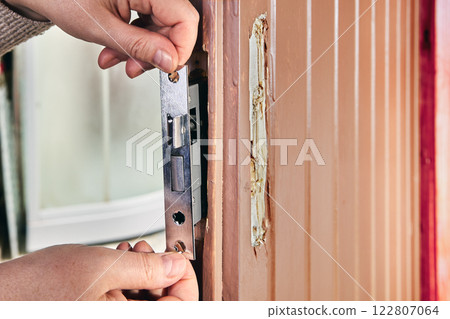 Locksmith fitting mortice lock into wooden door. Locksmith fitting mortice lock into wooden door. 122807064