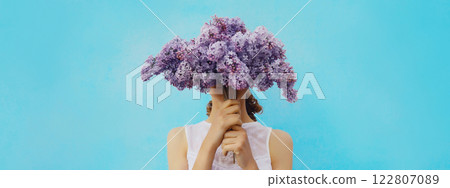 Portrait of woman covering her head with bouquet of fresh lilac flowers 122807089