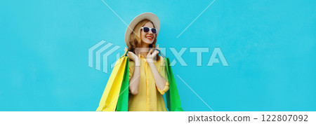 Fashion, clothing. Stylish beautiful happy woman with colorful shopping bags in summer hat on blue 122807092