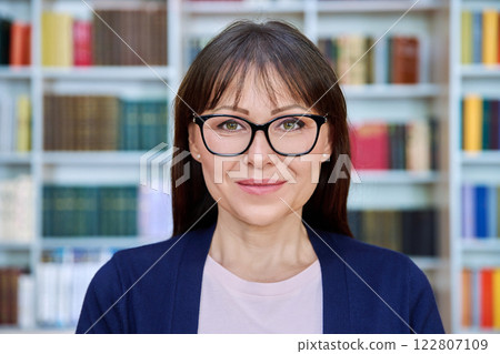 Headshot portrait of friendly mature woman in glasses inside library office Headshot portrait of friendly mature woman in glasses inside library office 122807109