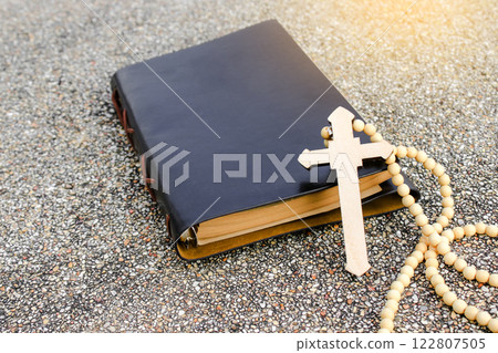 A white ivory cross placed on a dark brown notebook reflects purity, peace, and divine guidance. The contrast symbolizes light amidst darkness, faith, and personal devotion. 122807505