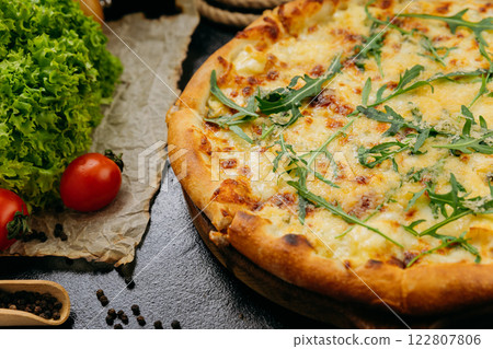 Gourmet four-cheese pizza with arugula, served on a wooden board in a stylish restaurant setting 122807806