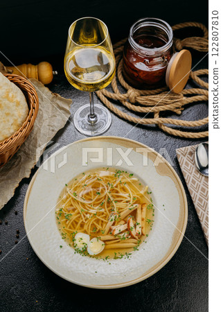 Clear broth soup with noodles, mushrooms, quail eggs, and herbs, served in an gourmet presentation 122807810