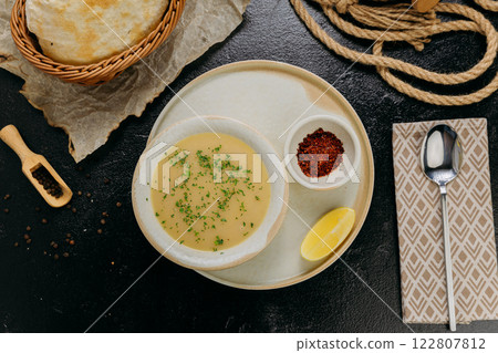 Creamy lentil soup with flatbread, sesame seeds, chili flakes, and lemon, served in an elegant style 122807812