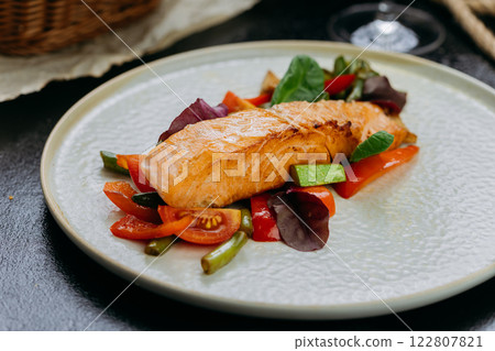 Grilled salmon fillet with fresh vegetables, served on a plate, elegant food presentation Grilled salmon fillet with fresh vegetables, served on a plate, elegant food presentation 122807821