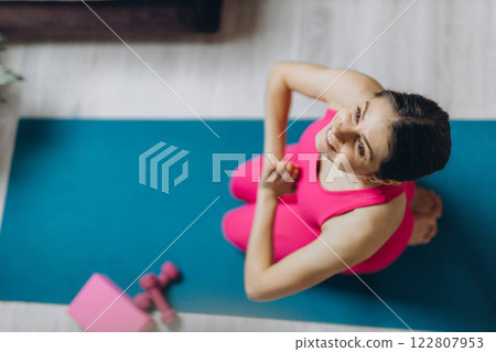 A top view of a girl in a stretching sports outfit with two pink dumbbells visible.Space for text 122807953