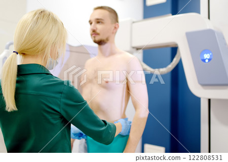 Female radiologist is making an Xray of lungs of patient in X-ray room of modern clinic. Doctor performs a fluorography. Medical examination of people is prevention of tuberculosis spread 122808531