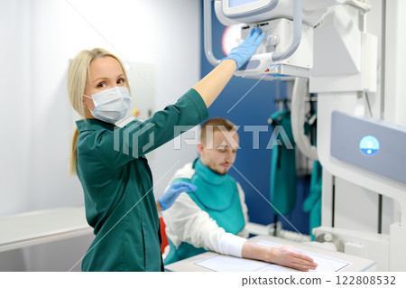Young man having x-ray shot of broken hand in x ray room in modern clinic. Patient wearing in protect lead apron 122808532
