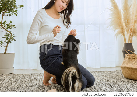 Woman playing with her dog in the living room 122808796
