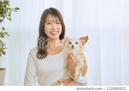 Woman playing with her dog in the living room 122808832