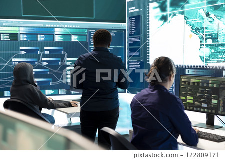 Governmental hackers exploiting network systems in high tech office, executing cyber operations for national server security. Focus on data protection and online safety to combat cybercrime. 122809171