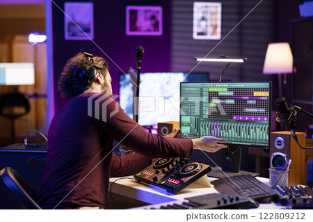 Musical artist using usb stick to edit past audio recordings on daw software interface, working with mixing console and stereo tools. Producer creating soundtracks and sound effects. Musical artist using usb stick to edit past audio recordings on daw software interface, working with mixing console and stereo tools. Producer creating soundtracks and sound effects. 122809212
