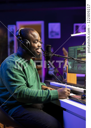 Professional songwriter composing a new song on paper, thinking about melodic elements to blend together. Composer artist producing new music in home studio, working on chorus and rhymes. 122809217