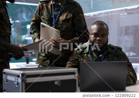 Military analysts in a modern control center power base overseeing reconnaissance tasks, coordinate security protocols and collect real time data for field operations. Control tower activity. Military analysts in a modern control center power base overseeing reconnaissance tasks, coordinate security protocols and collect real time data for field operations. Control tower activity. 122809222