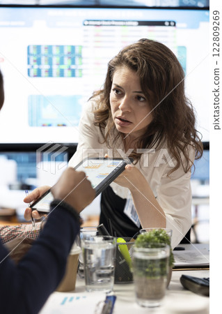 Project manager and staff engaging in a collaborative briefing meeting, using the interactive board and data visualization tools to present potential expansion solutions and enhance outcomes. 122809269