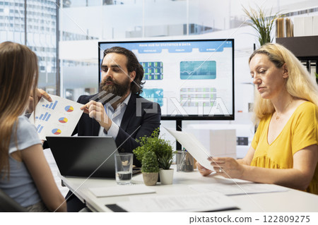 Financial advisor showing clients forex trends charts, diagrams and economic indicators. Broker using large display to present mom and gen Z girl strategies to identify investment opportunities 122809275