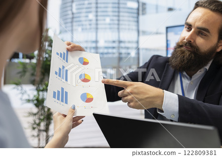 Financial advisor works with young adult to create long term investment strategies, close up. Agent helps gen Z girl set realistic financial goals and roadmap, showing her charts 122809381