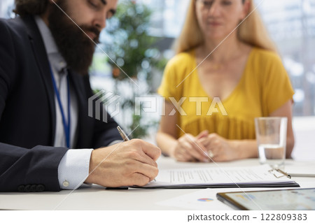 Financial advisor creating reports on investment performance and activity, filling paperwork forms. Close up shot of agent writing documents, developing portfolio maximizing financial gains 122809383