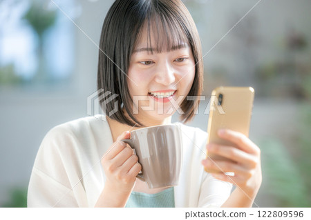 A young woman operating a smartphone 122809596