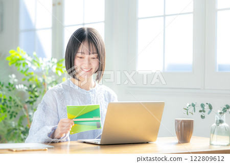 一個女人看著她的銀行存摺和電腦 122809612