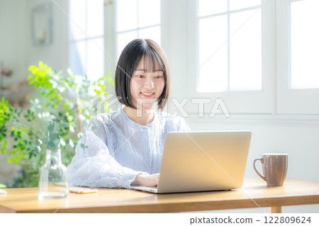 使用一台電腦在客廳裡的年輕女子 122809624