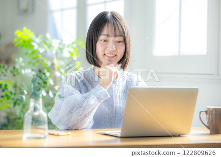 使用一台電腦在客廳裡的年輕女子 122809626
