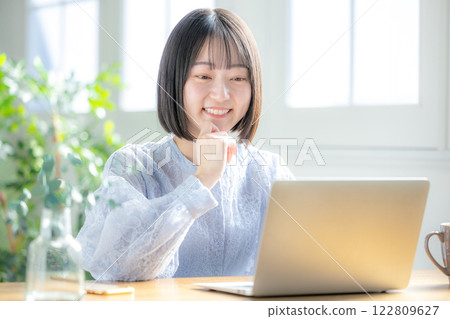 使用一台電腦在客廳裡的年輕女子 122809627