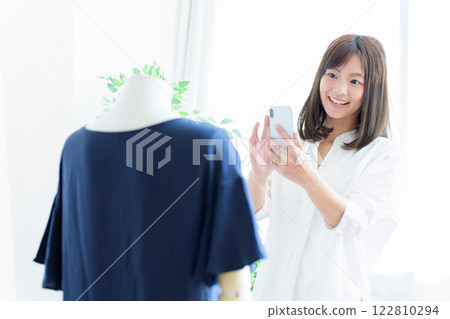 一名女子用智慧型手機拍攝衣服照片 122810294