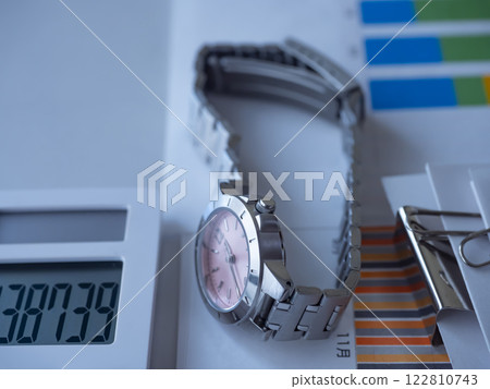 Graphs, documents, a calculator and a watch on a table Graphs, documents, a calculator and a watch on a table 122810743